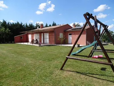 a swing set in a yard in front of a house at Villa bellevue in Fanjeaux