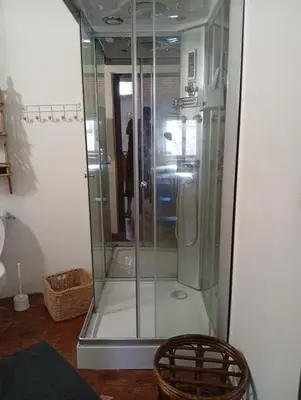 a glass shower in a room with two chairs at Appartement prémian in Prémian