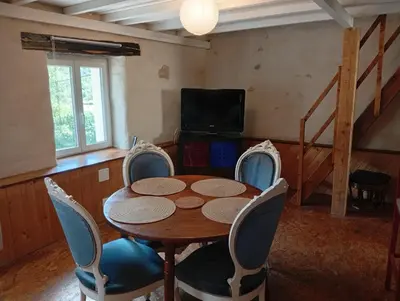 a dining room with a table and chairs and a television at Appartement prémian in Prémian