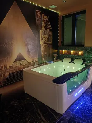 a bathroom with a tub with a statue in the background at Les cités romances Le Cléopâtre in Carcassonne