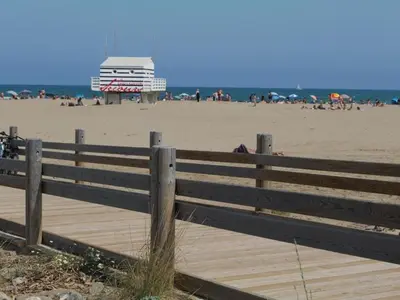 a wooden fence on a beach with a building in the background at Studio rénové centre Gruissan - 2 pers, parking privé - FR-1-796-92 in Gruissan