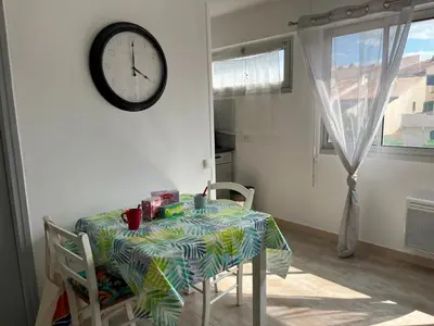 a table and chairs with a clock on a wall at Studio rénové centre Gruissan - 2 pers, parking privé - FR-1-796-92 in Gruissan