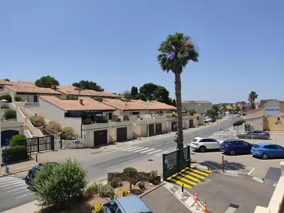 a city street with a palm tree and a parking lot at Studio rénové centre Gruissan - 2 pers, parking privé - FR-1-796-92 in Gruissan