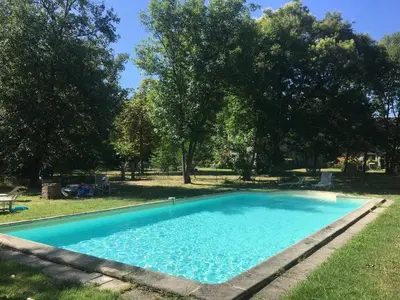 a blue swimming pool in a yard with trees at chateaubelleauboisdormant in Cambounet-sur-le-Sor