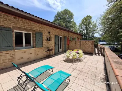a patio with chairs and tables and a building at Gites Villa Robinson in Mazamet