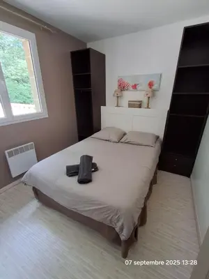 a bedroom with a large bed with a black purse on it at Gites Villa Robinson in Mazamet