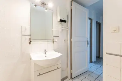 a white bathroom with a sink and a mirror at Le Parc de la Révolution - Proche Gare in Narbonne