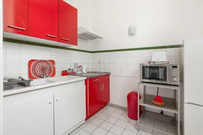 a kitchen with red cabinets and a microwave at Le Parc de la Révolution - Proche Gare in Narbonne