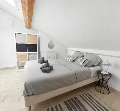 a white bedroom with a large bed with pillows at Appartement Lumineux Carcassonne Centre in Carcassonne