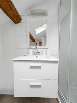 a white bathroom with a sink and a mirror at Appartement Lumineux Carcassonne Centre in Carcassonne