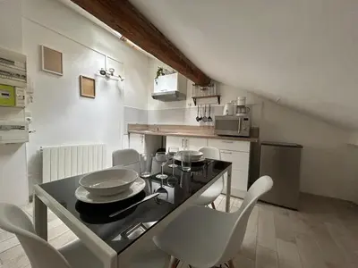 a kitchen with a table and white chairs in a room at Appartement Lumineux Carcassonne Centre in Carcassonne