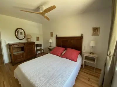 a bedroom with a bed with red pillows and a ceiling fan at En joia ! in Teyssode