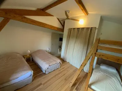 two beds in a room with wooden floors at En joia ! in Teyssode