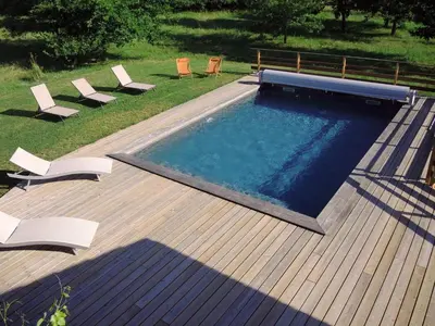 a swimming pool on a deck with chairs around it at En joia ! in Teyssode