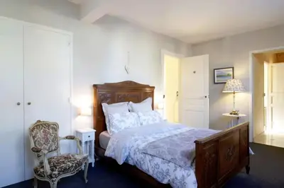 a bedroom with a large bed and a chair at Maison de maître à BRAM # Jacuzzi in Bram