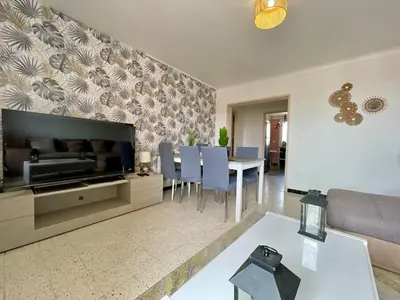 a living room with a television and a dining room at Le Strasbourg - 3 chambres - parking et terrasse in Carcassonne
