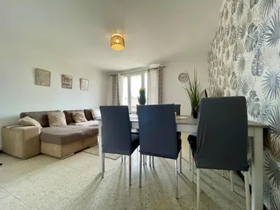 a living room with a table and chairs and a couch at Le Strasbourg - 3 chambres - parking et terrasse in Carcassonne