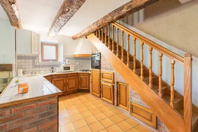 a kitchen with wooden cabinets and a staircase at La Pause Verte - 30min de Castre in Montredon-Labessonnié