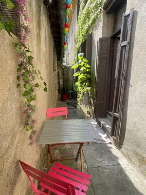 two red chairs and a wooden table in an alley at Appartement avec Patio in Carcassonne