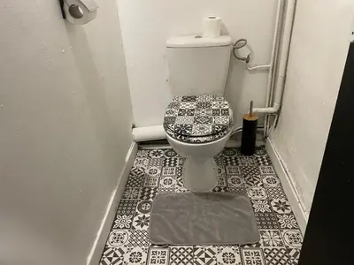 a bathroom with a toilet with a tile floor at Appartement avec Patio in Carcassonne