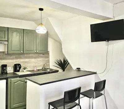 a kitchen with green cabinets and a counter with chairs at Les Studios de la Bastide in Carcassonne