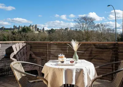 a table on a balcony with a view of the city at Maison La Djoon,Vue Cité, centre ville Spa Jardin in Carcassonne