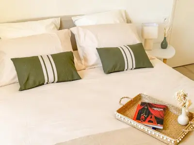 a white bed with green pillows and a tray on it at Maison La Djoon,Vue Cité, centre ville Spa Jardin in Carcassonne