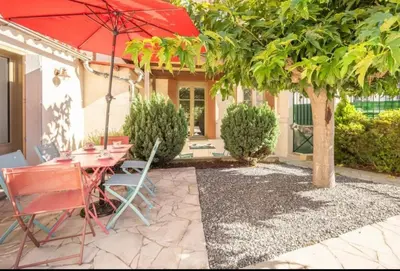 a patio with a table and chairs and a red umbrella at Maison La Djoon,Vue Cité, centre ville Spa Jardin in Carcassonne