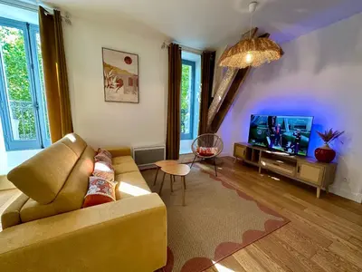 a living room with a couch and a tv at Appartement T2 Méditerranéen in Narbonne