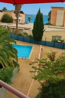 a view of a swimming pool from the balcony of a house at 2 appartements mitoyens avec climatisation, piscine et parking - Plages et Port à 100m in Gruissan