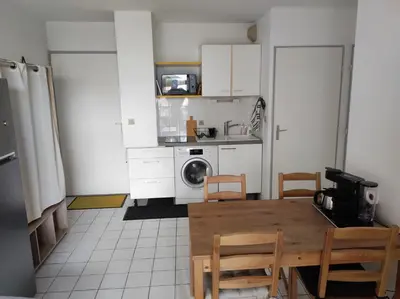 a kitchen with a table and chairs in a kitchen at 2 appartements mitoyens avec climatisation, piscine et parking - Plages et Port à 100m in Gruissan
