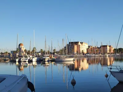 a group of boats docked in a harbor with buildings at 2 appartements mitoyens avec climatisation, piscine et parking - Plages et Port à 100m in Gruissan