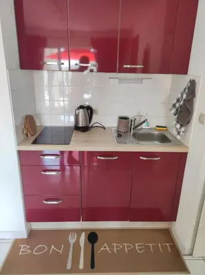 a kitchen with red cabinets and a sink at 2 appartements mitoyens avec climatisation, piscine et parking - Plages et Port à 100m in Gruissan
