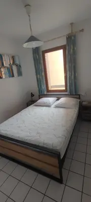 a bed in a room with a window at 2 appartements mitoyens avec climatisation, piscine et parking - Plages et Port à 100m in Gruissan
