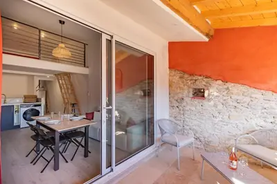 a dining room with a table and a stone wall at La Cité Merveilleuse - Cité - Clim - Wifi in Carcassonne