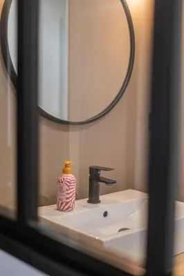a bathroom sink with a soap dispenser and a mirror at 203 Balcon de la Bastide in Carcassonne