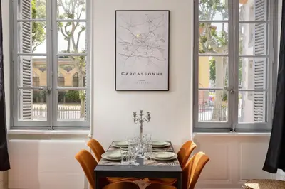 a dining room with a table and chairs and windows at T2 Design Centre Cité 10 min in Carcassonne