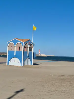 a blue and white building on the beach with a lighthouse at Mobile Home climatisé 2 chambres Port La Nouvelle in Port-la-Nouvelle