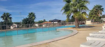 a large swimming pool with palm trees in a resort at Mobile Home climatisé 2 chambres Port La Nouvelle in Port-la-Nouvelle