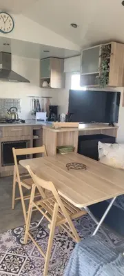 a kitchen with a wooden table and two chairs at Mobile Home climatisé 2 chambres Port La Nouvelle in Port-la-Nouvelle
