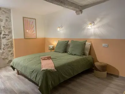 a bedroom with a green bed with a pink towel on it at Suites zen dans maison d'hôtes avec piscine intérieure et jardin in Ventenac-Cabardès
