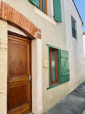 a building with green shutters and a wooden door at Canalentin in Castelnaudary