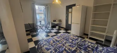 a room with a bed and a kitchen with a refrigerator at Chambre 1 - avec grande terrasse in Port-la-Nouvelle