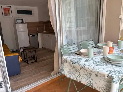 a dining room table with a table and chairs and a kitchen at Ondine in Gruissan