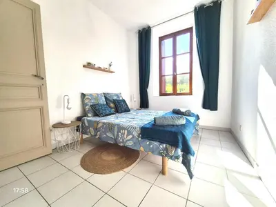 a bedroom with a bed with blue sheets and a window at Charmant T2 au pied de la Cité de Carcassonne- AL in Carcassonne