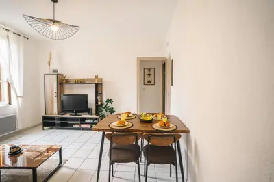 a living room with a wooden table and chairs at Charmant T2 au pied de la Cité de Carcassonne- AL in Carcassonne