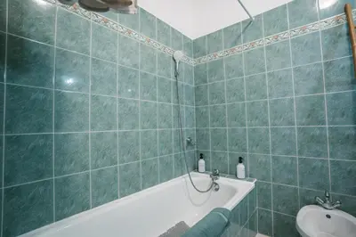 a green tiled bathroom with a tub and a sink at Charmant T2 au pied de la Cité de Carcassonne- AL in Carcassonne