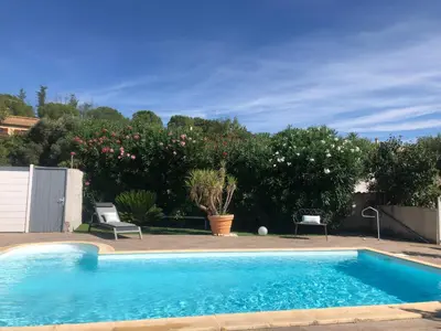a blue swimming pool with two chairs and trees at Villa Bel Air in Puisserguier