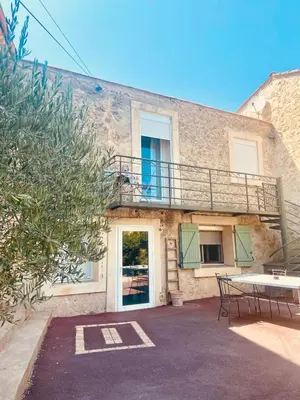 a building with a balcony and a table and bench at Villa Bel Air in Puisserguier
