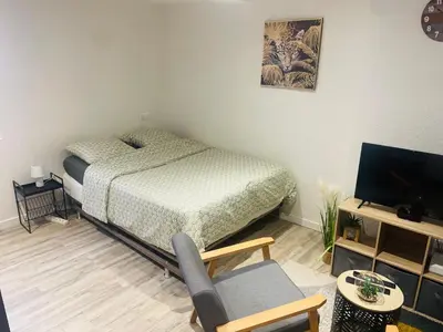 a bedroom with a bed and a chair and a television at Studette narbonaise in Narbonne